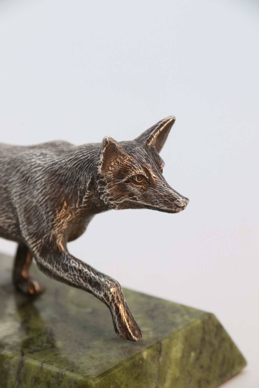 A silvered bronze sculpture depicting a prowling fox mounted on a rectangular green marble plinth. View XI