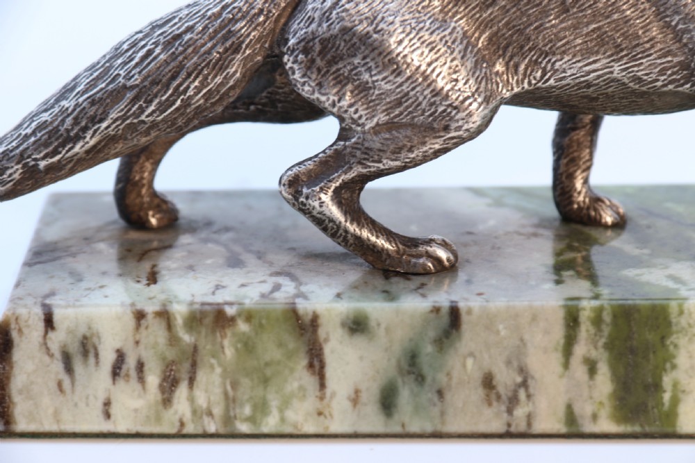 A silvered bronze sculpture depicting a prowling fox mounted on a rectangular green marble plinth. View XIII