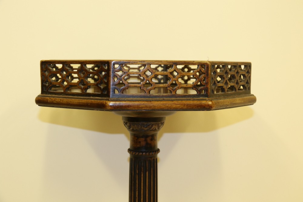 An antique Chippendale mahogany candle stand featuring an octagonal top with a pierced fretwork gallery, a fluted column, and carved tripod legs. View II