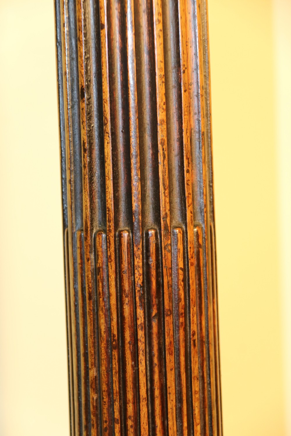 An antique Chippendale mahogany candle stand featuring an octagonal top with a pierced fretwork gallery, a fluted column, and carved tripod legs. View V