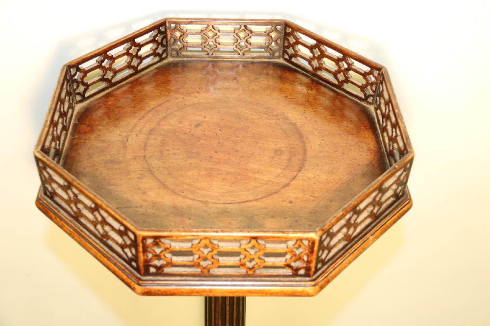 An antique Chippendale mahogany candle stand featuring an octagonal top with a pierced fretwork gallery, a fluted column, and carved tripod legs. View XVII