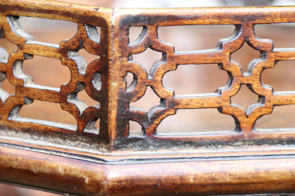 An antique Chippendale mahogany candle stand featuring an octagonal top with a pierced fretwork gallery, a fluted column, and carved tripod legs. View XXI