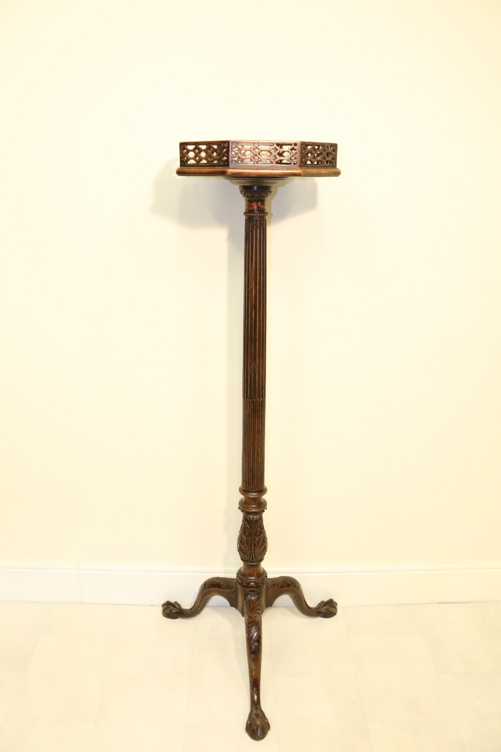 An antique Chippendale mahogany candle stand featuring an octagonal top with a pierced fretwork gallery, a fluted column, and carved tripod legs. View XXIV