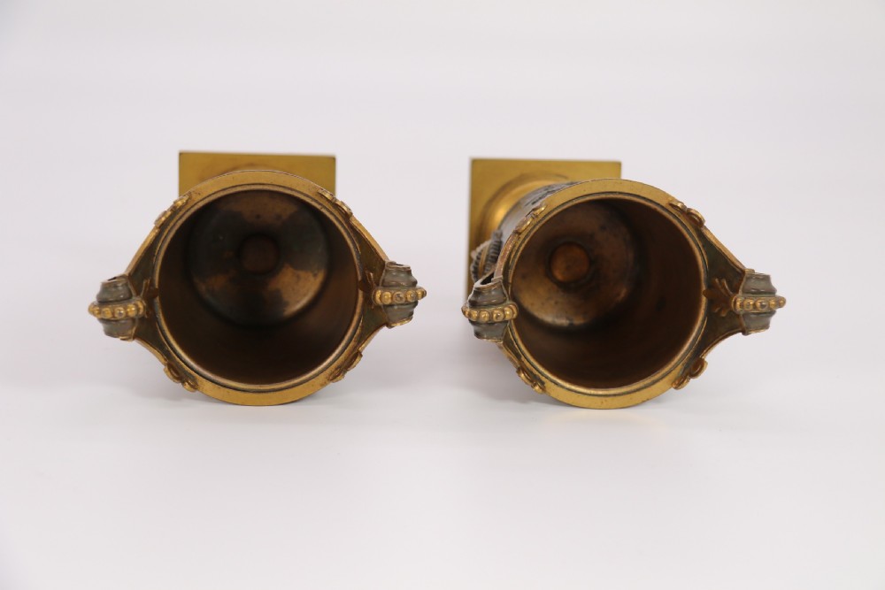 A pair of French Empire patinated and gilt bronze urns with Greek key friezes, scroll handles, and square bases. View XXVII