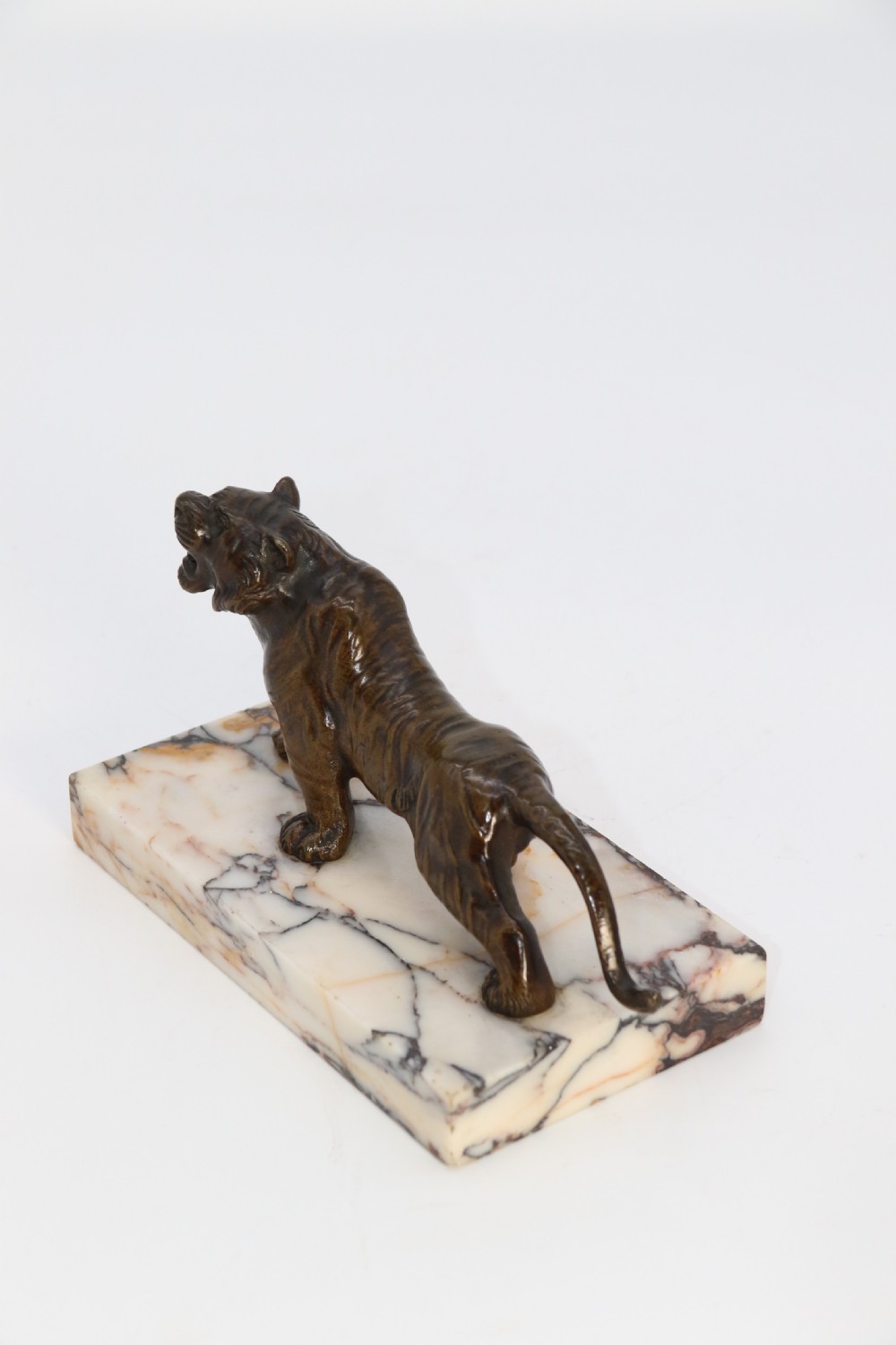 A dark bronze tiger sculpture posed in a roaring stance, mounted on a rectangular veined marble base. View VII