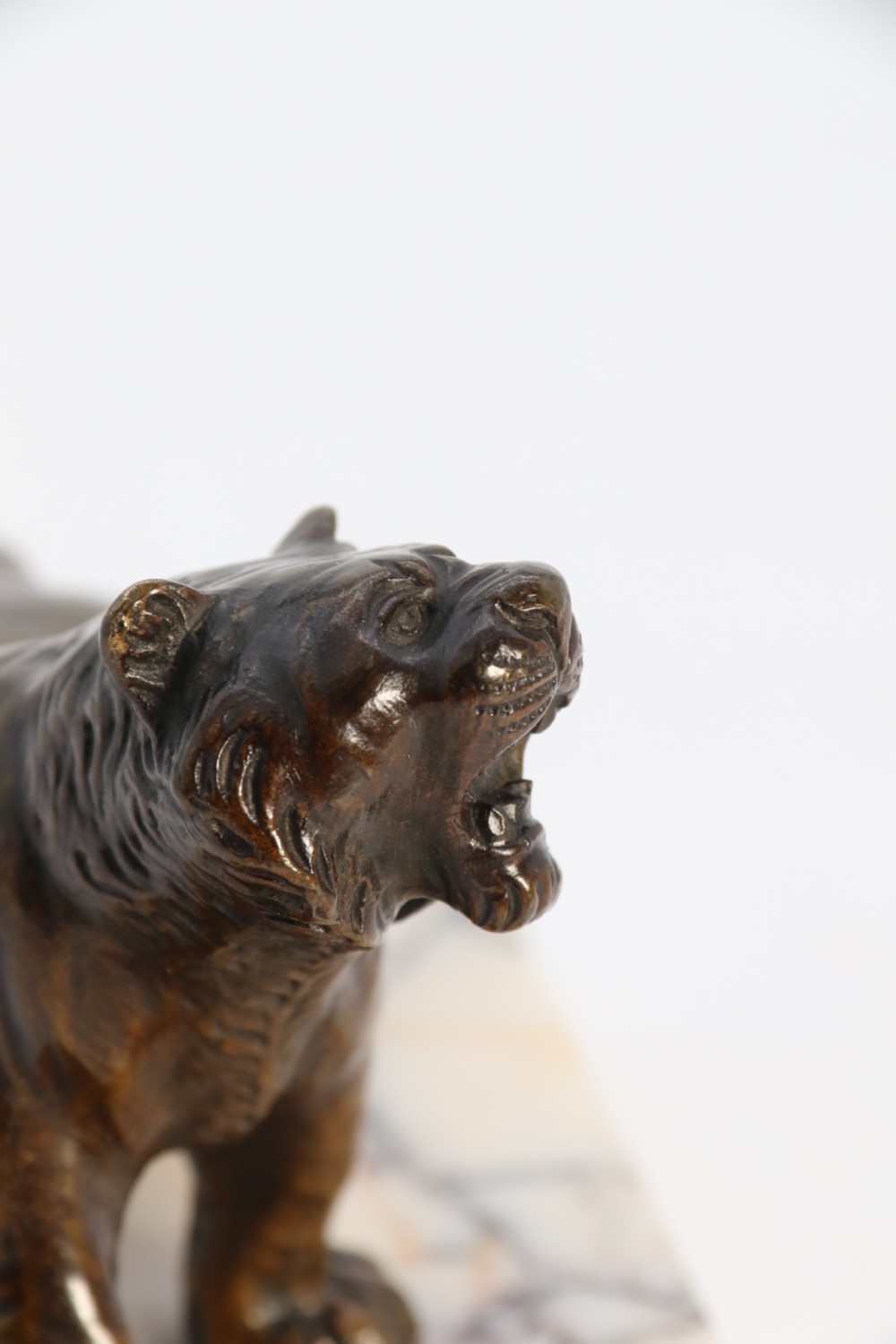A dark bronze tiger sculpture posed in a roaring stance, mounted on a rectangular veined marble base. View XV
