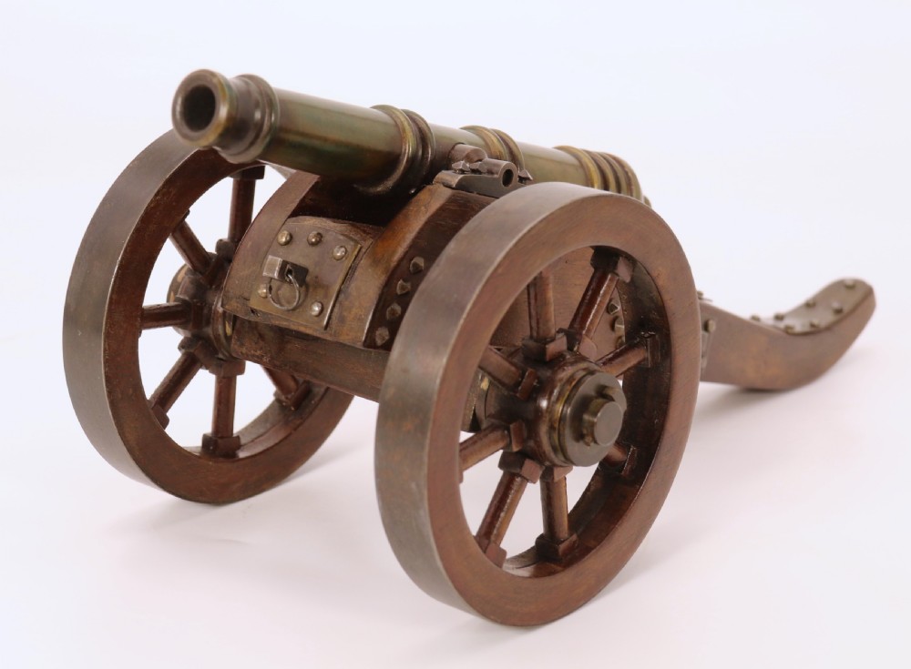 A detailed hand-built scale model of a 17th-century field cannon featuring a patinated brass barrel mounted on a dark timber carriage with spoked wheels. View IV