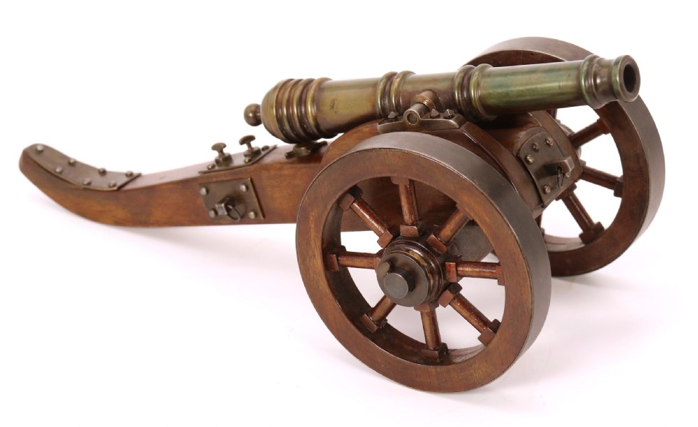 A detailed hand-built scale model of a 17th-century field cannon featuring a patinated brass barrel mounted on a dark timber carriage with spoked wheels. View IX