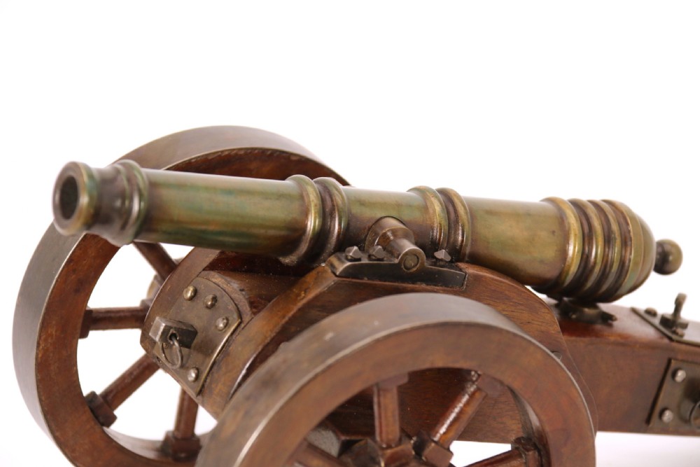 A detailed hand-built scale model of a 17th-century field cannon featuring a patinated brass barrel mounted on a dark timber carriage with spoked wheels. View XIV