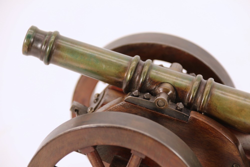 A detailed hand-built scale model of a 17th-century field cannon featuring a patinated brass barrel mounted on a dark timber carriage with spoked wheels. View XX