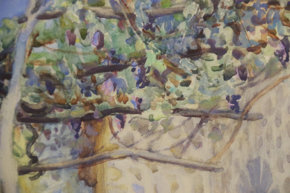 A framed 1920s watercolour landscape painting showing a stone building with vine foliage, set inside a decorative gilt frame with cream matting. View VII