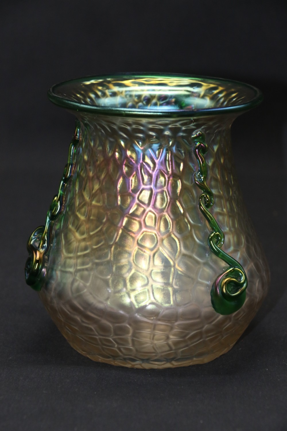 An Art Nouveau iridescent glass vase featuring a textured honeycomb pattern, a flared rim, and dark green applied glass trailings along the sides. View XI
