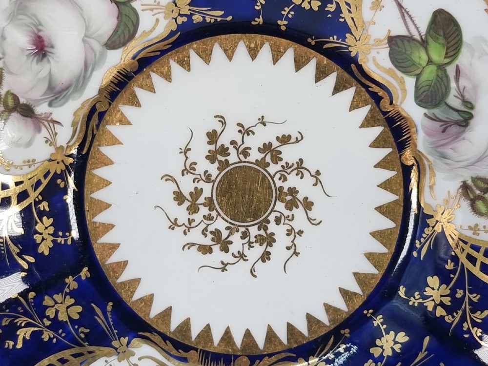 An early nineteenth-century Coalport porcelain cabinet trio featuring a teacup, coffee cup, and saucer styled with cobalt blue borders, gilded detailing, and hand-painted white rose panels. View III