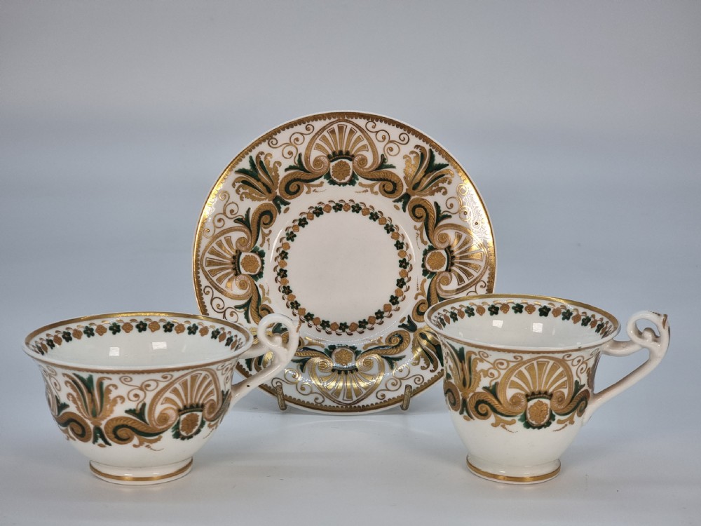 An early 19th-century Spode porcelain cabinet trio consisting of a teacup, coffee cup, and saucer adorned with intricate gold gilding and green scrollwork. View XXX