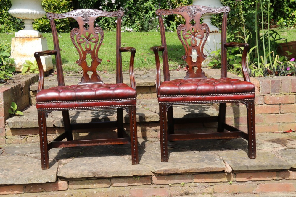 A pair of 18th-century George III Chippendale period mahogany armchairs featuring pierced carved back splats and deep red buttoned leather seats with brass stud trim. View III
