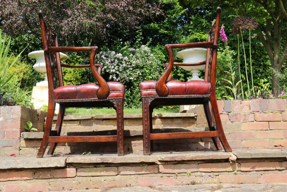A pair of 18th-century George III Chippendale period mahogany armchairs featuring pierced carved back splats and deep red buttoned leather seats with brass stud trim. View V