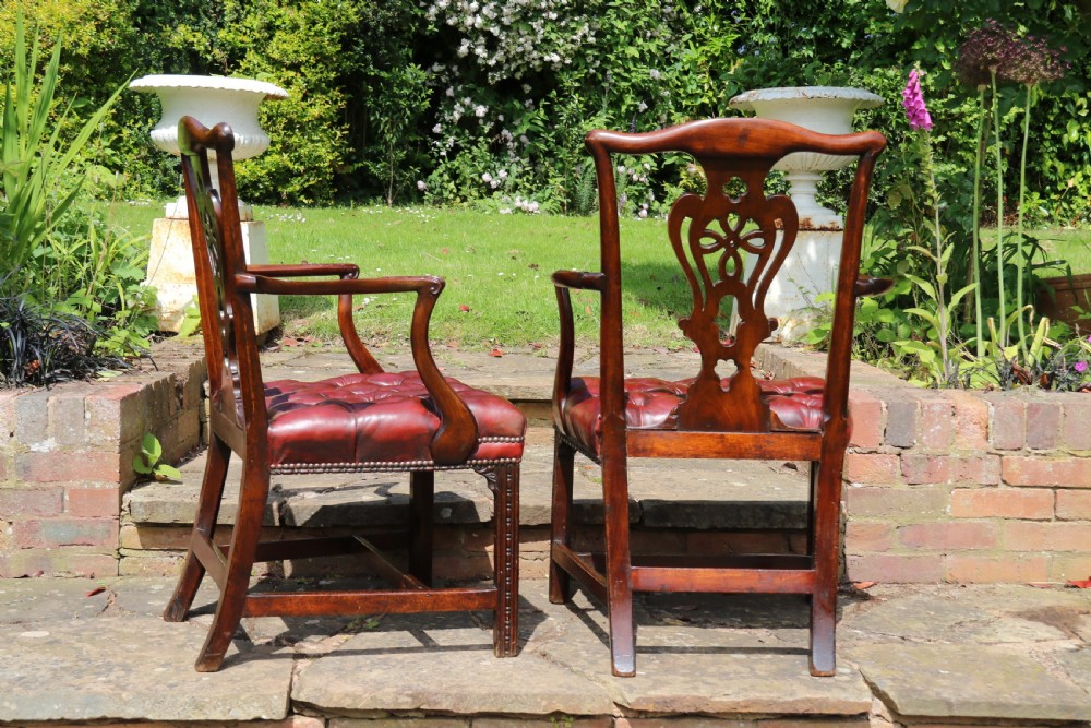 A pair of 18th-century George III Chippendale period mahogany armchairs featuring pierced carved back splats and deep red buttoned leather seats with brass stud trim. View VI