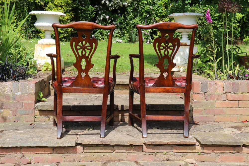 A pair of 18th-century George III Chippendale period mahogany armchairs featuring pierced carved back splats and deep red buttoned leather seats with brass stud trim. View VII