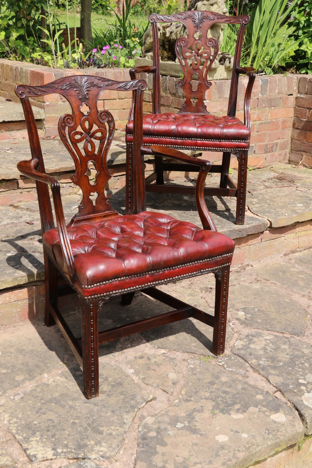 A pair of 18th-century George III Chippendale period mahogany armchairs featuring pierced carved back splats and deep red buttoned leather seats with brass stud trim. View VIII