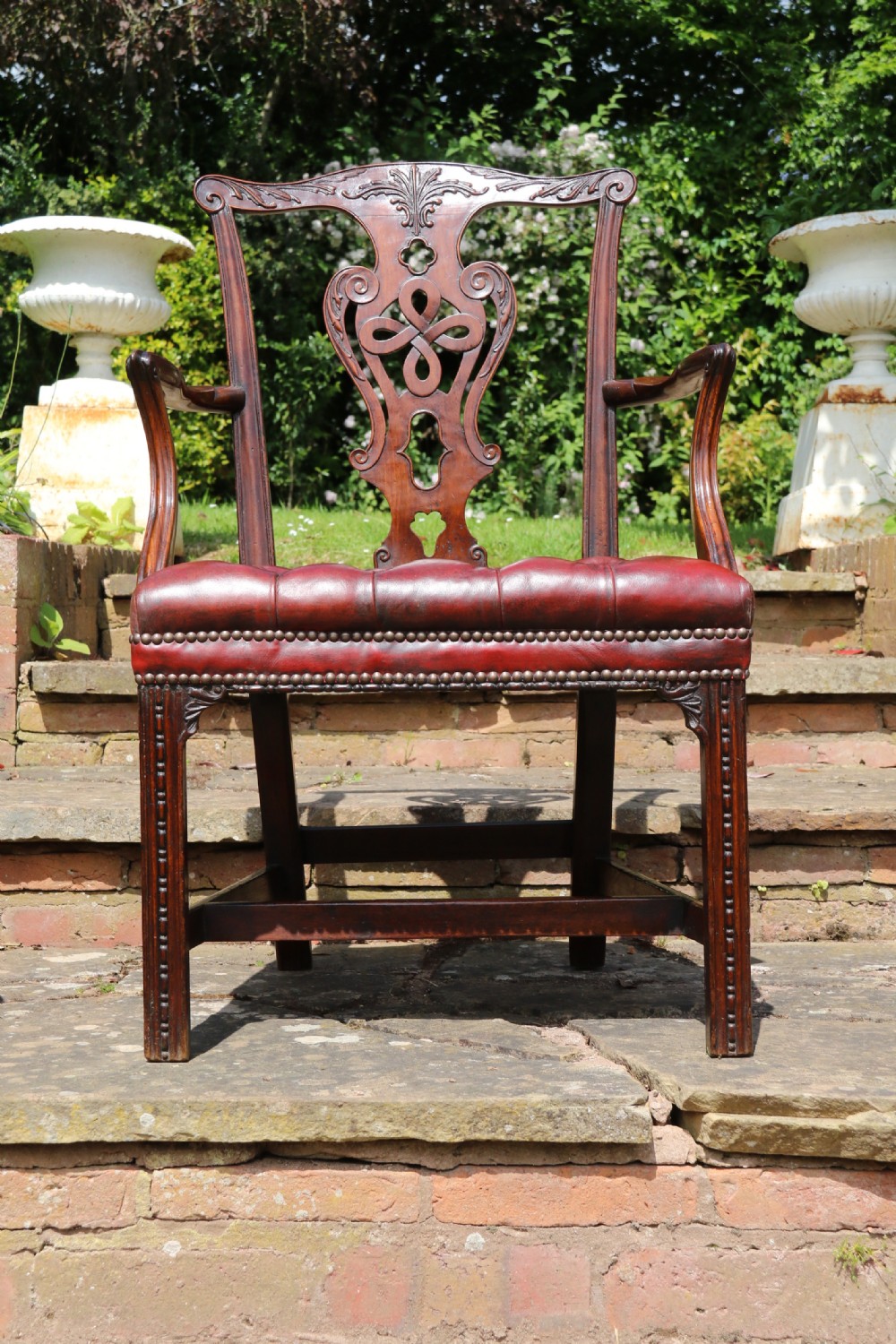 A pair of 18th-century George III Chippendale period mahogany armchairs featuring pierced carved back splats and deep red buttoned leather seats with brass stud trim. View IX