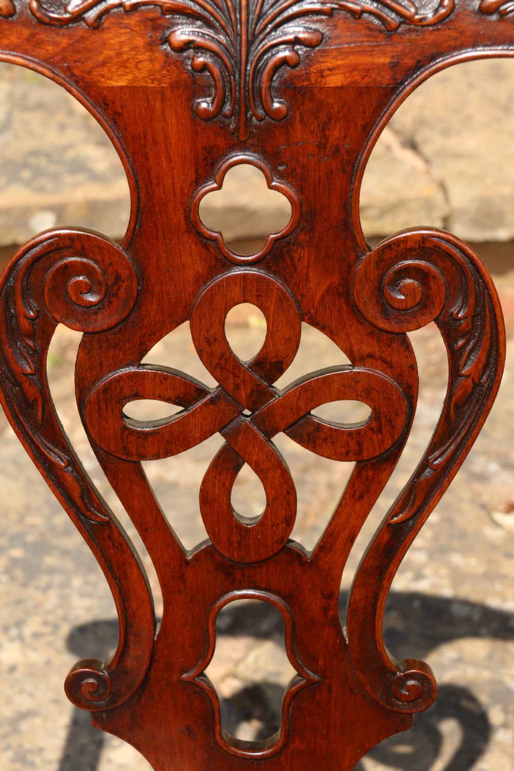 A pair of 18th-century George III Chippendale period mahogany armchairs featuring pierced carved back splats and deep red buttoned leather seats with brass stud trim. View XII