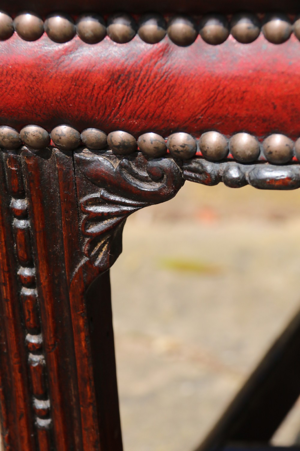 A pair of 18th-century George III Chippendale period mahogany armchairs featuring pierced carved back splats and deep red buttoned leather seats with brass stud trim. View XVII