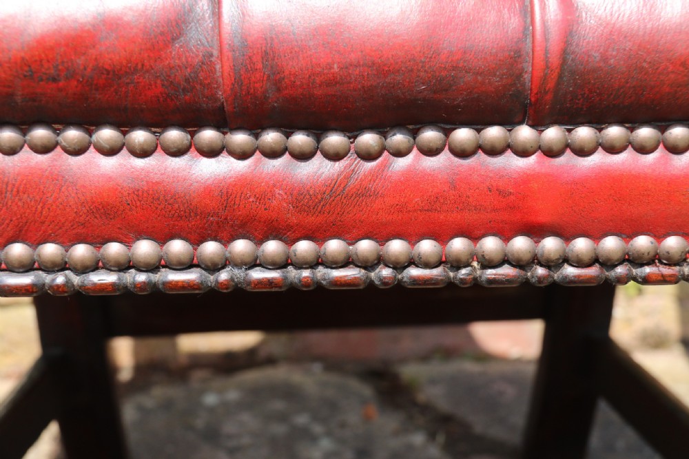 A pair of 18th-century George III Chippendale period mahogany armchairs featuring pierced carved back splats and deep red buttoned leather seats with brass stud trim. View XIX