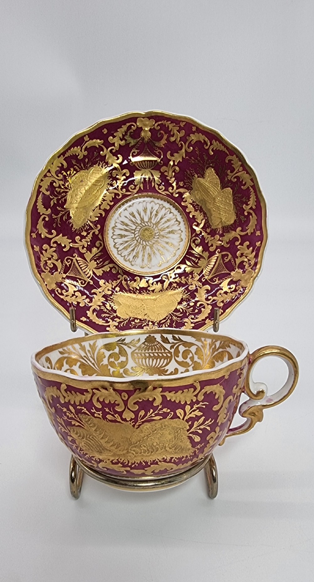 An early nineteenth-century Spode cabinet cup and matching saucer featuring a deep magenta ground embellished with heavy gold leaf scrollwork.