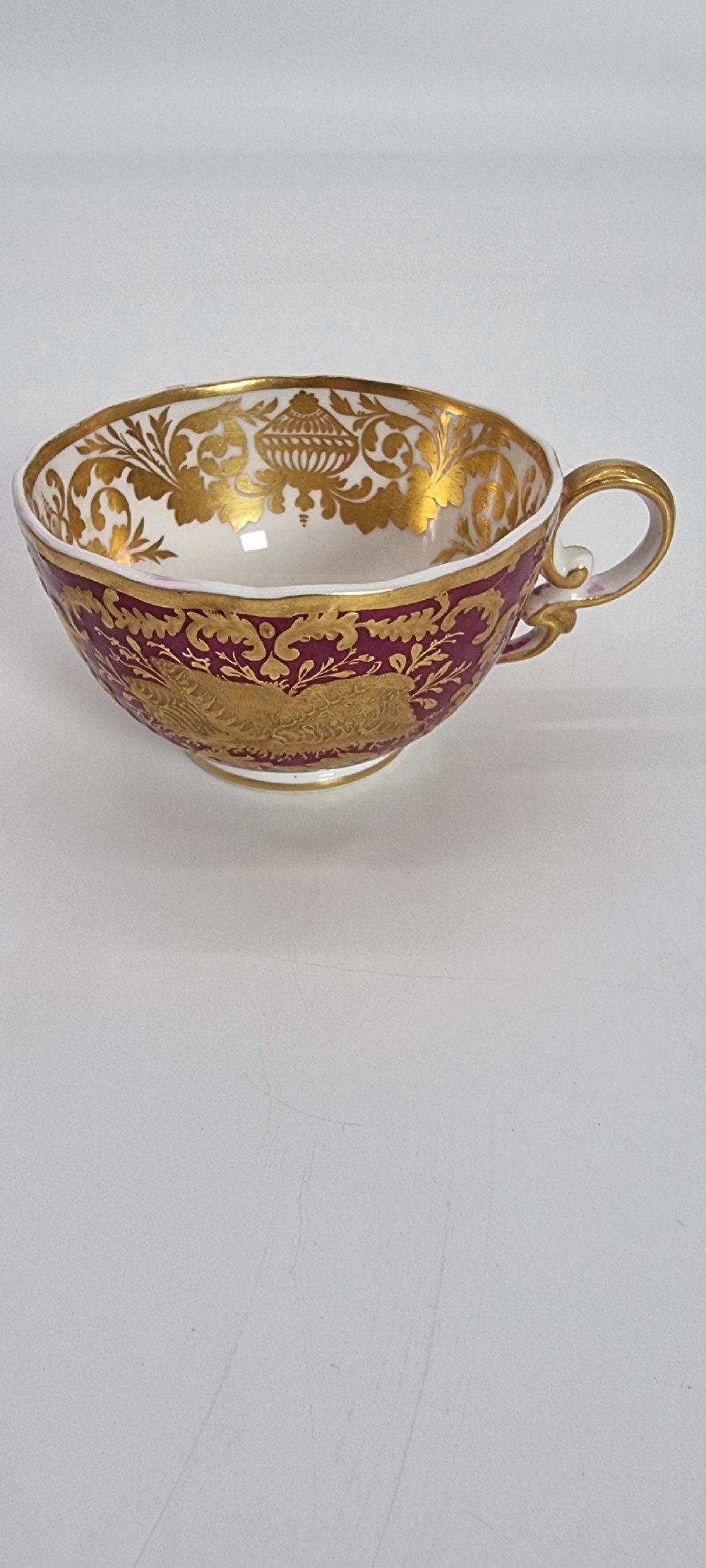An early nineteenth-century Spode cabinet cup and matching saucer featuring a deep magenta ground embellished with heavy gold leaf scrollwork. View X