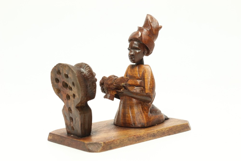A collection of hand-carved warm brown hardwood figures from Nigeria depicting individuals engaged in daily tasks alongside a carved canoe. View IV