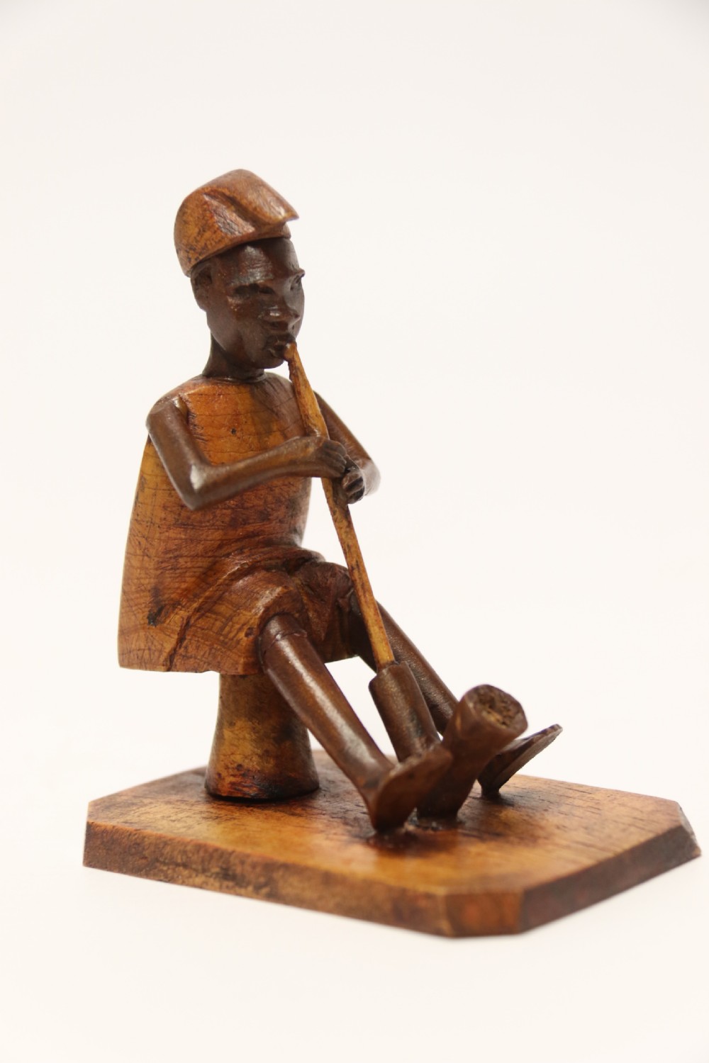 A collection of hand-carved warm brown hardwood figures from Nigeria depicting individuals engaged in daily tasks alongside a carved canoe. View VIII