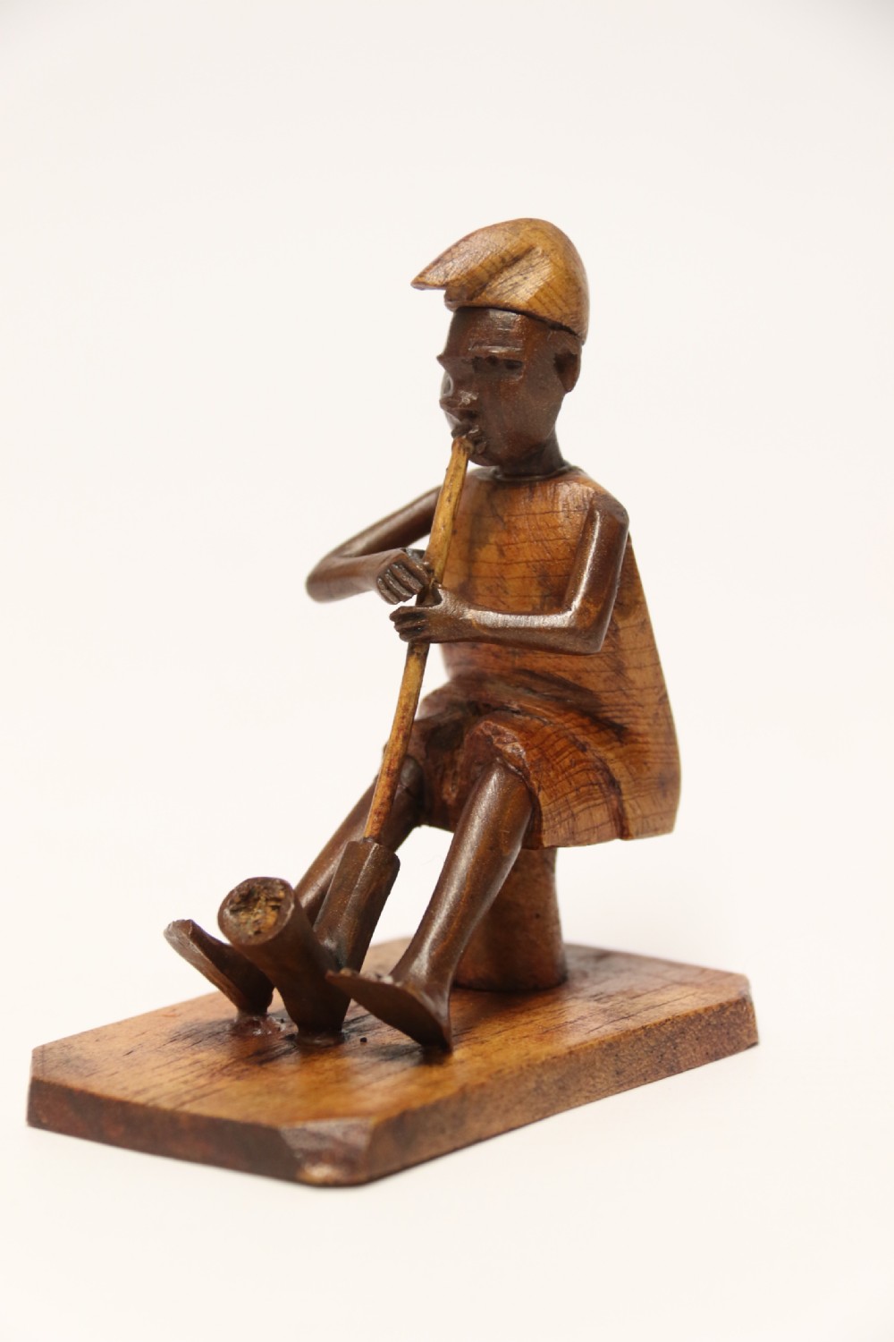 A collection of hand-carved warm brown hardwood figures from Nigeria depicting individuals engaged in daily tasks alongside a carved canoe. View IX