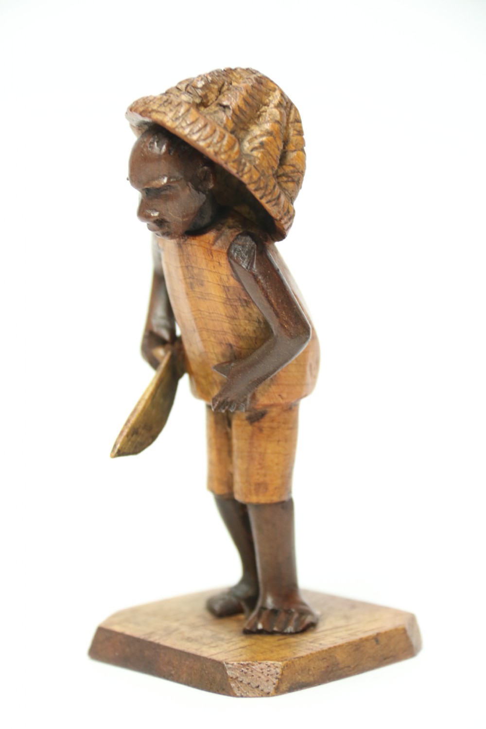 A collection of hand-carved warm brown hardwood figures from Nigeria depicting individuals engaged in daily tasks alongside a carved canoe. View XI