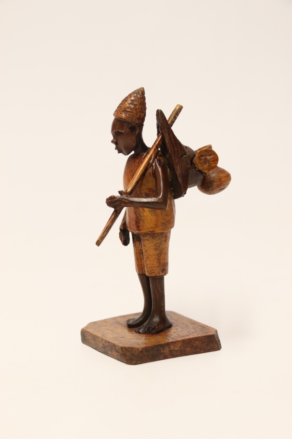 A collection of hand-carved warm brown hardwood figures from Nigeria depicting individuals engaged in daily tasks alongside a carved canoe. View XIII
