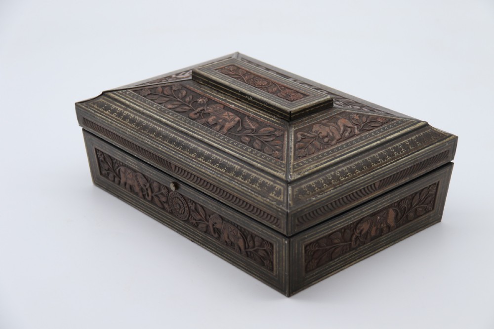 A rectangular lithographed tinplate box with a stepped lid, featuring embossed floral and elephant motifs designed to simulate carved wood. View IX