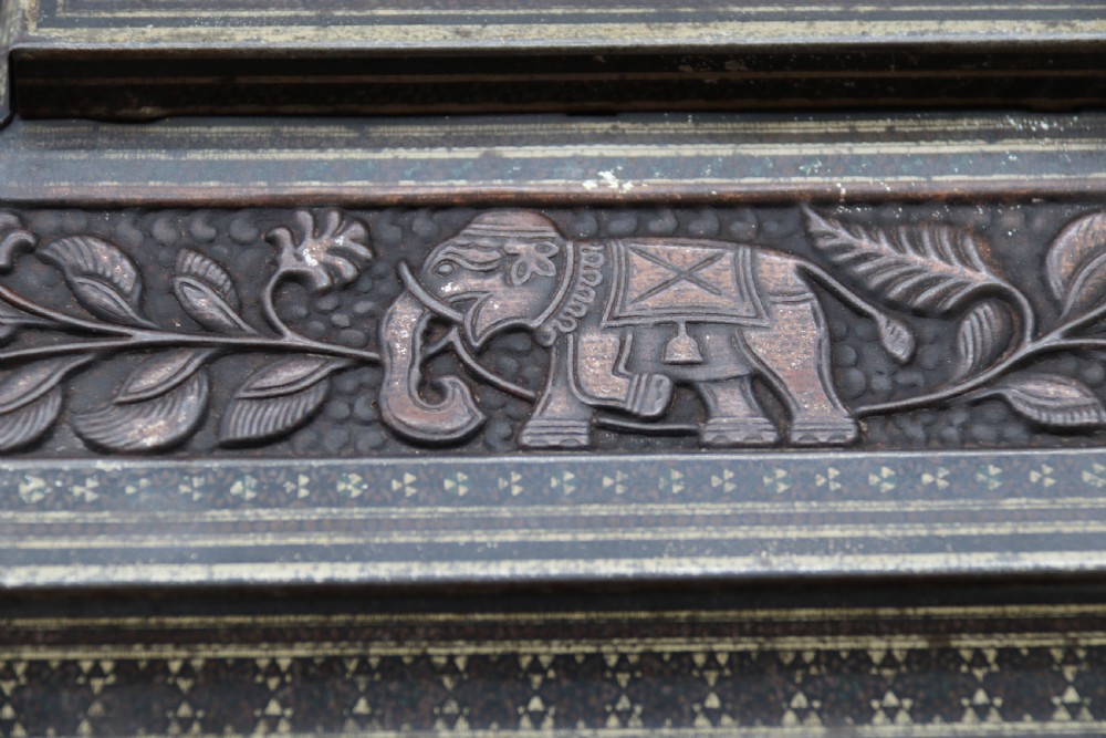 A rectangular lithographed tinplate box with a stepped lid, featuring embossed floral and elephant motifs designed to simulate carved wood. View XIV