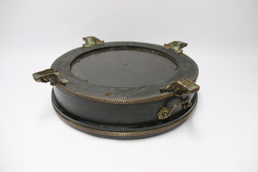 An antique French roulette wheel with ebonised wood casing and brass claw feet, set in front of an original dark green felt layout cloth printed with gold French gaming text. View III