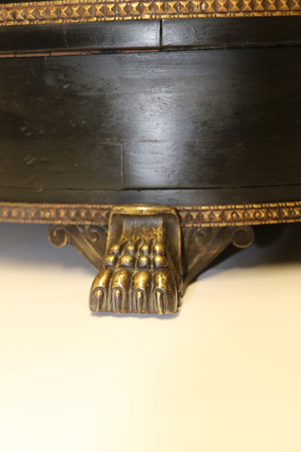 An antique French roulette wheel with ebonised wood casing and brass claw feet, set in front of an original dark green felt layout cloth printed with gold French gaming text. View XV