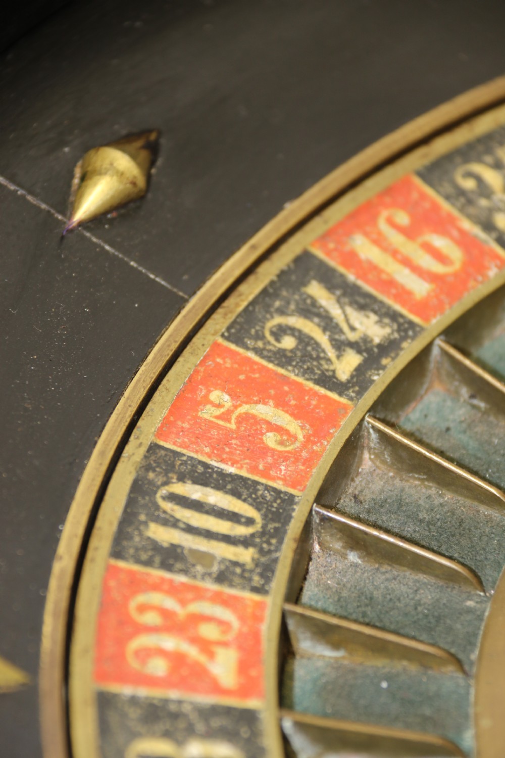 An antique French roulette wheel with ebonised wood casing and brass claw feet, set in front of an original dark green felt layout cloth printed with gold French gaming text. View XVIII