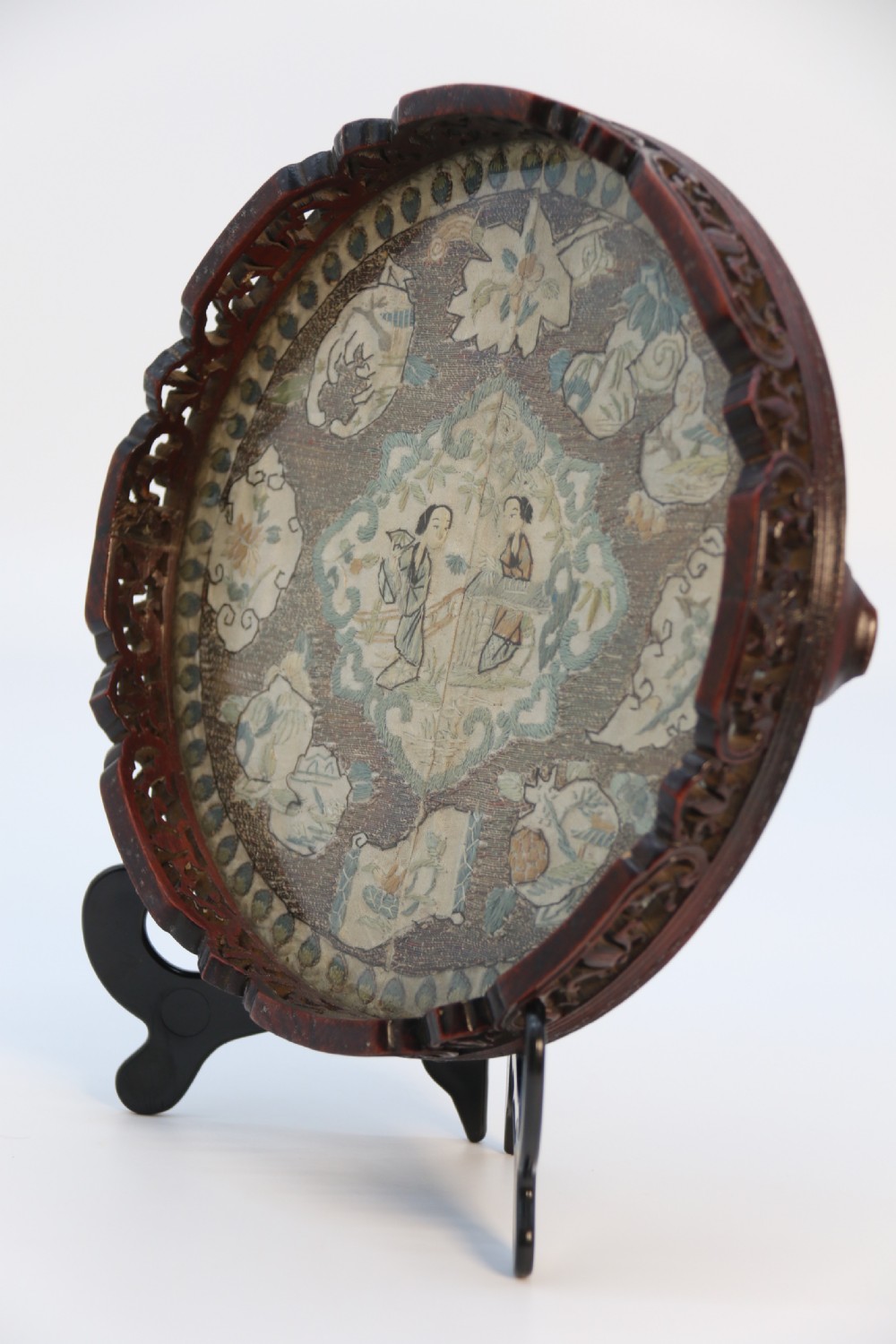 A circular carved dark hardwood tray containing an inset 19th-century Chinese silk embroidery with figural and botanical motifs. View III