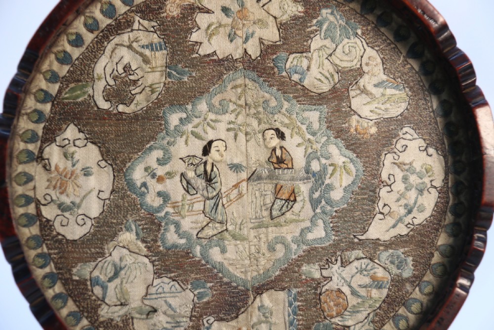 A circular carved dark hardwood tray containing an inset 19th-century Chinese silk embroidery with figural and botanical motifs. View VI