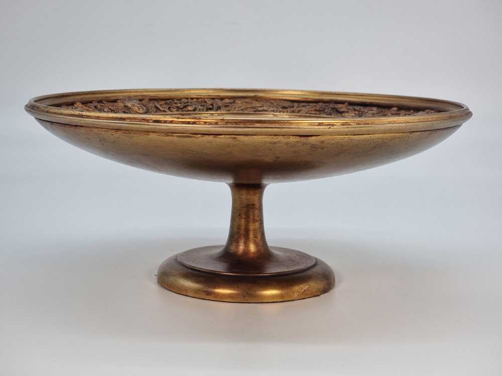 An Aesthetic Movement circular gilt metal tazza on a pedestal foot featuring ornate foliate scrollwork and a central relief medallion. View VIII
