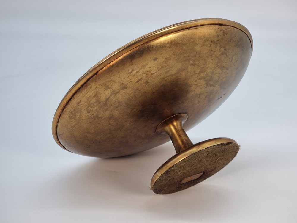 An Aesthetic Movement circular gilt metal tazza on a pedestal foot featuring ornate foliate scrollwork and a central relief medallion. View X