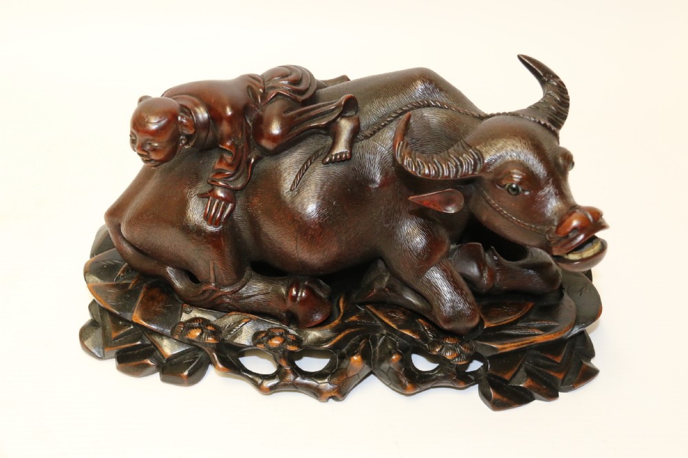 A pair of late Qing dynasty hand-carved dark hardwood water buffaloes, each mounted on a pierced wooden base and depicting a small boy resting on its back. View XIII