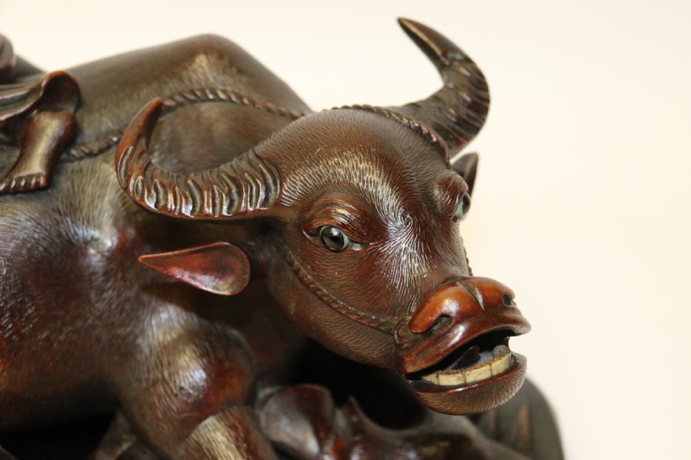 A pair of late Qing dynasty hand-carved dark hardwood water buffaloes, each mounted on a pierced wooden base and depicting a small boy resting on its back. View XIV
