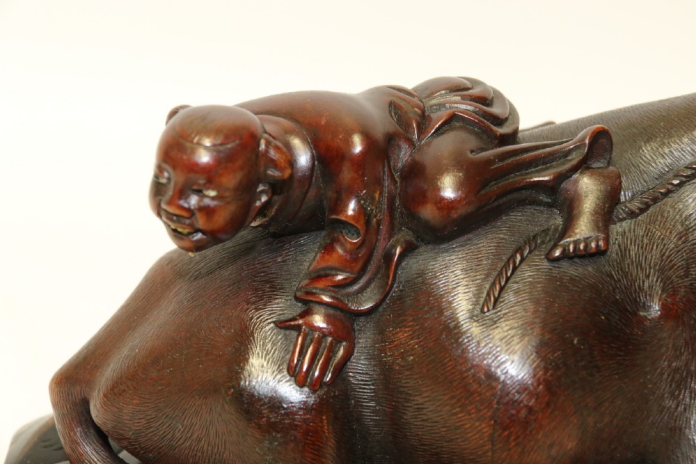 A pair of late Qing dynasty hand-carved dark hardwood water buffaloes, each mounted on a pierced wooden base and depicting a small boy resting on its back. View XV