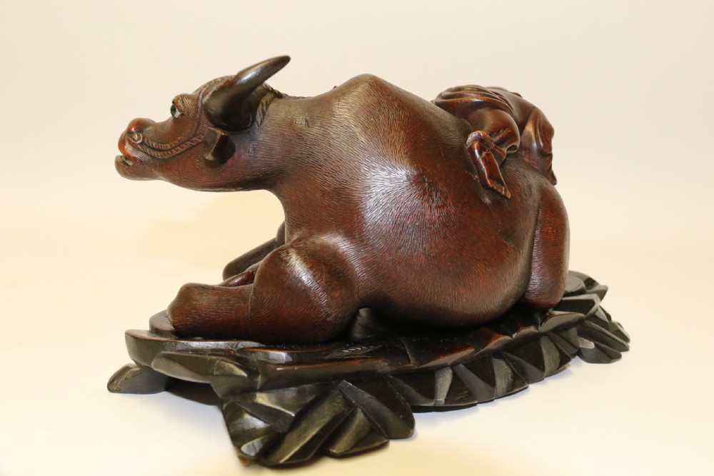 A pair of late Qing dynasty hand-carved dark hardwood water buffaloes, each mounted on a pierced wooden base and depicting a small boy resting on its back. View XIX