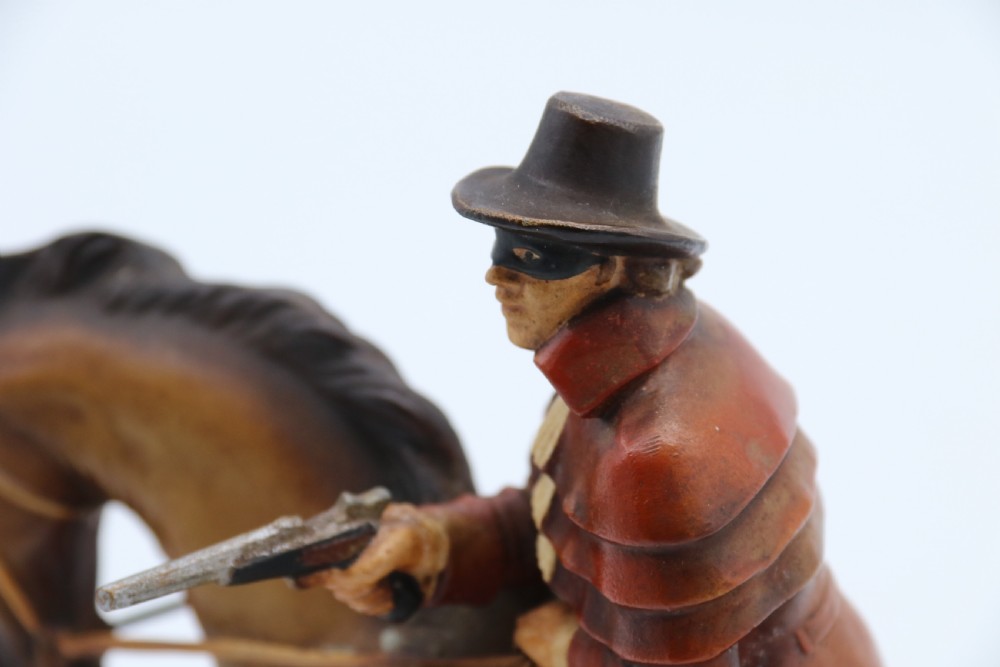 An Art Deco cold-painted metal figure of a masked highwayman on horseback mounted on a rectangular wooden plinth, featuring an integrated table lighter mechanism. View XVII