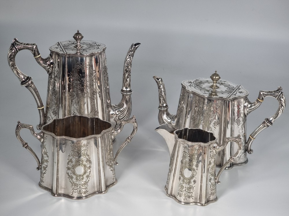 A four-piece Victorian silver-plated tea and coffee set featuring detailed engraving, fluted panels, and decorative handles.