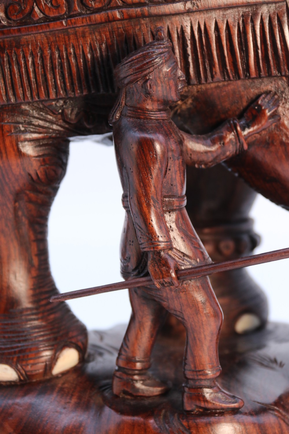 A dark hardwood sculpture depicting a ceremonial elephant adorned with decorative drapery accompanied by three mahouts on an integrated wooden base. View XI